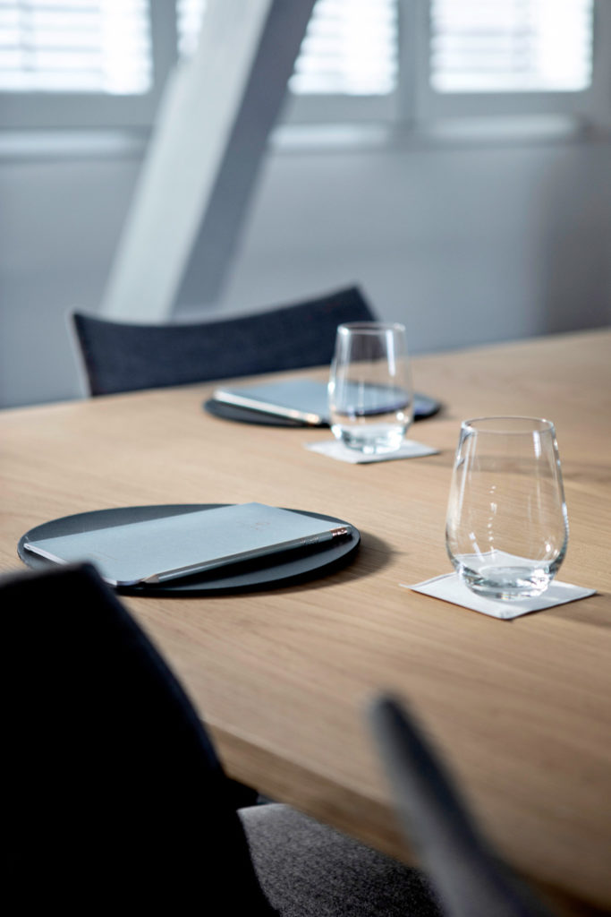 A close up of a meeting room table with an empty glass and a journal